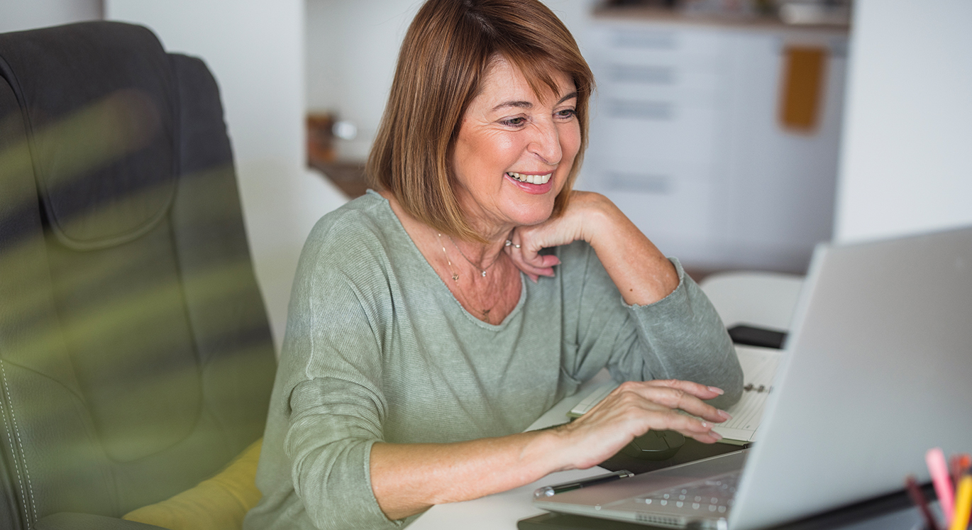 Frau sitzt im Büro am Schreibtisch und nimmt an einem Onlinetalk teil.