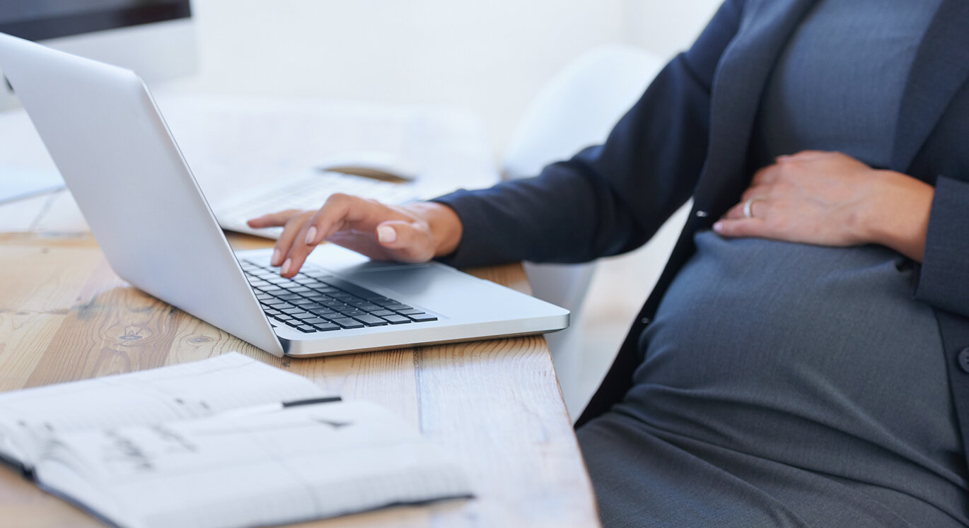 Schwangere informiert sich am Laptop zum Thema Elternzeit und Mutterschutz. | © iStock/PeopleImages