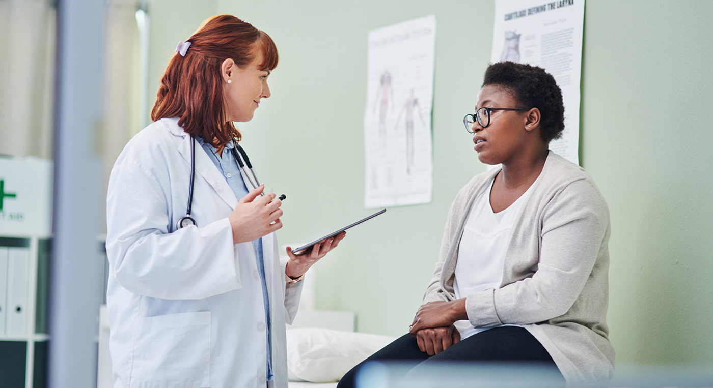 Patientin sitzt auf der Behandlungsliege und spricht mit ihrer Hausärztin.