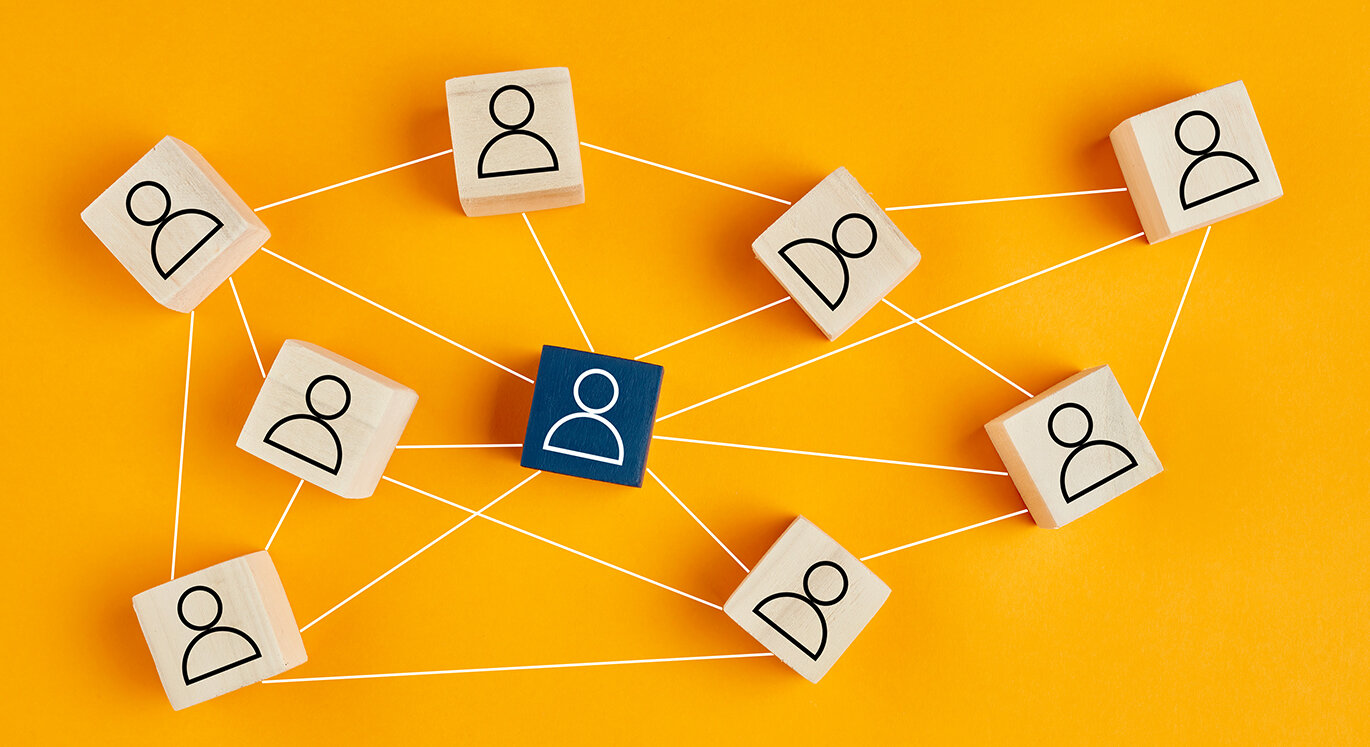 Mehrere Holzwürfel mit Personen-Icon sind mit einer gespannten Schnur verbunden. | © iStock/cagkansayin