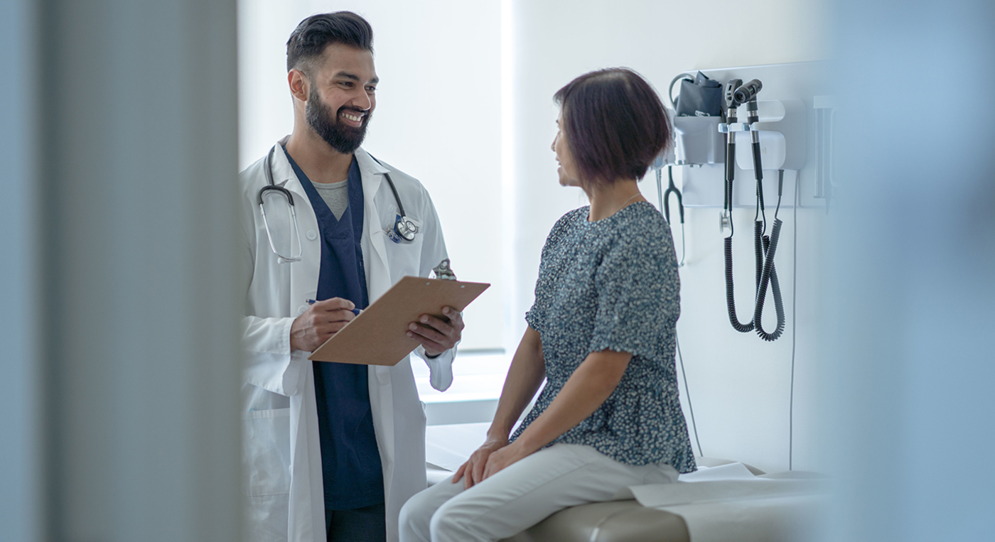 Junger Hausarzt im Gespräch mit einer Patientin in der Praxis.
