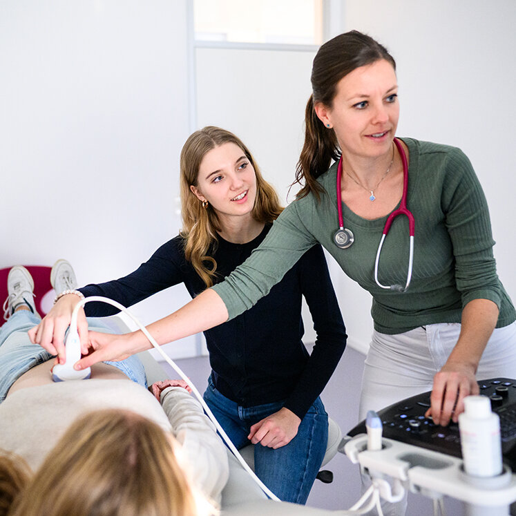 Medizinstudierende und Hausärztin untersuchen eine junge Patientin mit dem Ultraschall-Gerät. | © Tom Weller
