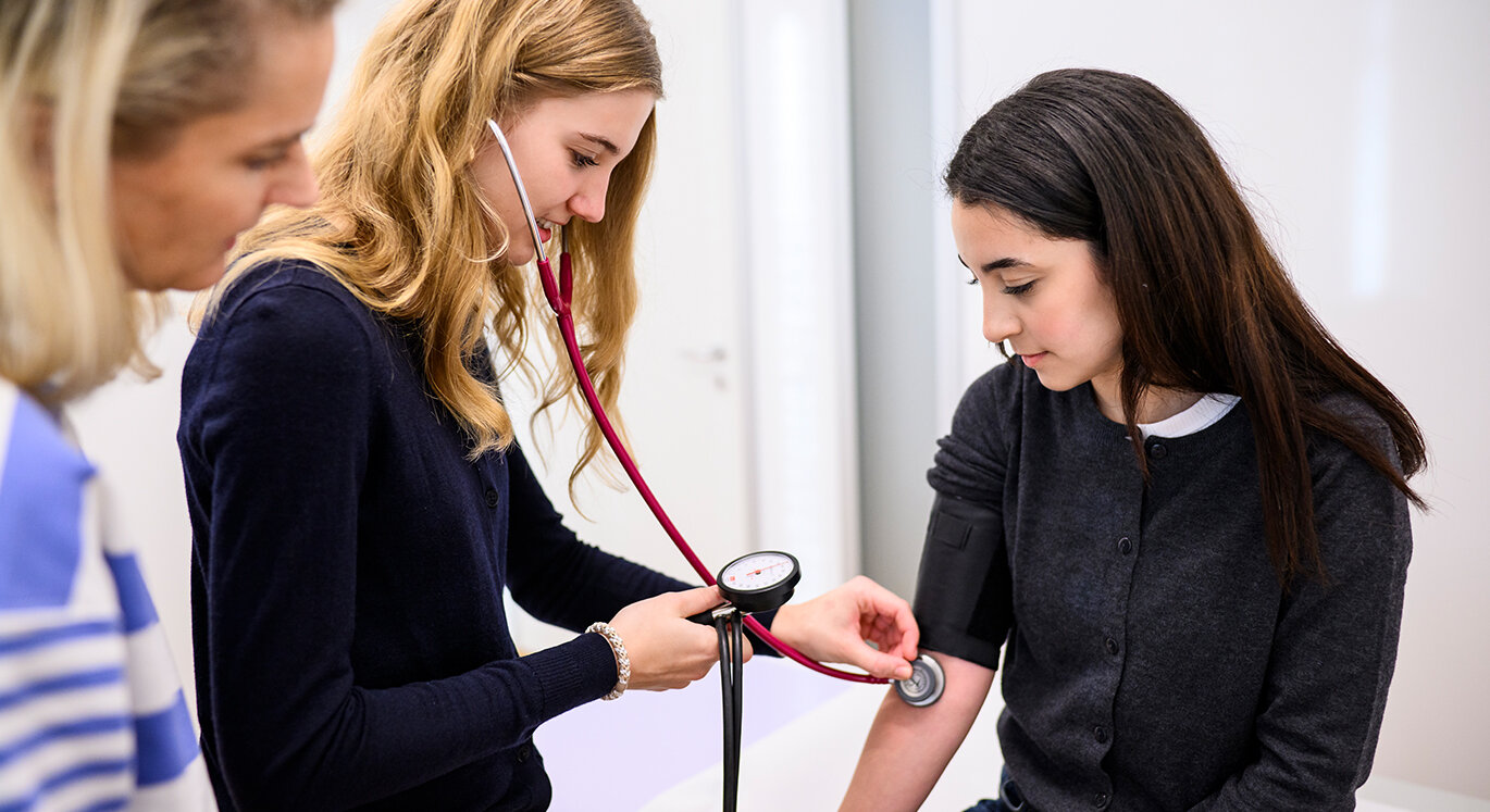 Medizinstudentin verwendet neben der Hausärztin das Stethoskop. | © Tom Weller