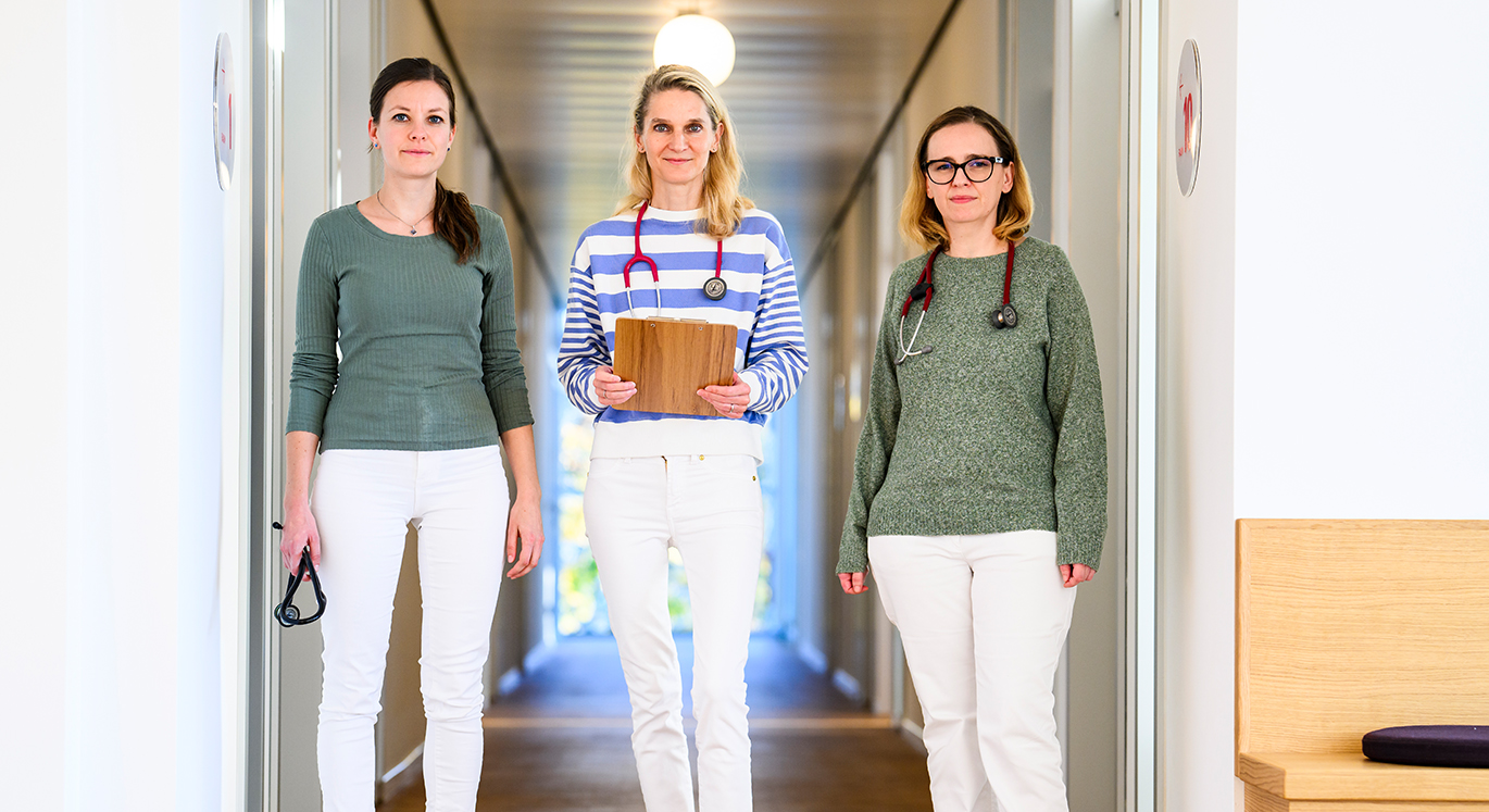 Drei Hausärztinnen stehen nebeneinander in der Praxis.